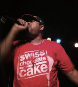 Mr. Complex  performing at album release wearing Swiss Chocolate Cake t-shirt